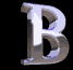 A single stylized letter B in metallic silver with blue highlights appears in multiple states across a black background, transitioning from sharp edges to blurred motion effects.