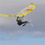 A static 50x50 pixel buddy icon depicting a stylized yellow running stick figure with black limbs and white accents, holding a long yellow object resembling a lacrosse or field hockey stick against a gradient sky background transitioning from light gray to blue.