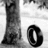 A grayscale pixelated image shows a tall, narrow figure with flowing hair and a long dress standing beside a large circular shape on the right.