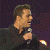 A 50x50 pixel animated contact sheet showing two frames of a Ricky Martin-themed buddy icon with green text on the right and a performer holding a microphone on the left.
