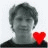 Two grayscale head-and-shoulders portraits of a person with short dark hair, one featuring a red heart symbol between them.