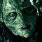 identical greenish alien faces with wide eyes and toothy grins, arranged in four against a dark background