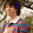 A person in a red and blue striped shirt with white collar stands outdoors, hand over chest, as text changes from 'I' to 'LOVE' then 'HIM <3'.