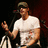 A pixelated image shows a person in a white t-shirt and cap holding a microphone, with red text reading 'adam gontier' on the right.