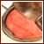 A pixelated close-up of a pinkish-red object resembling a tongue inside a mouth with brownish teeth and gums.