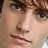 Pixelated close-up of a person's face showing eyes, nose, and mouth with brown hair and light skin tone.