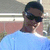 Pixelated image of a person with dark hair wearing sunglasses and a light blue shirt against a blurred background.