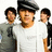 A split- image with a red background on the right and bottom, a white background on the top-left, and a gray on the bottom-right. The top-left shows three people with one wearing a dark cap and white shirt. The right displays yellow text reading "Why are the Jonas brothers" and the bottom-left shows "So HOT?" in yellow text