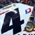 Animated scene of two motorcyclists racing on a track with spectators in the background, featuring bold black number '4' and red/blue circular symbols.