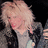 Pixelated image of a person with light-colored hair, closed eyes, and pinkish skin tones against dark background.