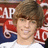 Pixelated image of a person with brown hair wearing a white shirt, set against a red and white background with partial text.