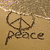 A sandy beach scene with a peace symbol drawn in the sand above the word "peace" written below it.