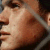 Pixelated close-up of a person's face showing nose, lips, and cheek with brown hair visible at top right corner.