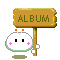 A 4-frame animated contact sheet showing a pixel art character with pink blush marks holding a wooden sign that reads "ALBUM" in green text, displayed on a gray background.