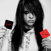 A person with long dark hair holds two small square cards, one black with red text and one red with black text, against a light background.
