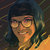Pixelated portrait of a person with dark hair and warm-toned skin, wearing a dark garment against a blurred background.