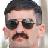 Static 48x48 pixel buddy icon showing a stylized male face with dark hair, sunglasses, and mustache on a light background.