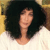 Pixelated image of a person with dark hair wearing a light-colored top against a blurred background.