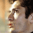 Pixelated close-up of a person's face with dark hair and light skin, showing partial facial features including an eye, nose, mouth, and ear against a blurred background.