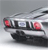 Pixelated image of a silver car with red taillights, viewed from a low angle against a gray background.