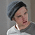 A pixelated image shows a person in a gray beanie and white shirt against a gray background, with green text reading "What the?" on the right side.