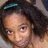 A pixelated close-up of a person with dark curly hair and light skin, wearing a teal hair clip on the left side.