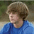 A pixelated image of a person with light brown hair wearing a blue shirt, next to bright purple background with green text.
