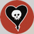 Static pixel art icon featuring a white skull centered within a black heart shape, all enclosed in a red circular border on a gray background.