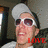 A person wearing a white cap and sunglasses with red-tinted lenses, smiling broadly while the word 'LOVE' appears in bold red text below.