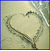 Two side-by-side animated frames showing a heart shape drawn in sand on a beach with palm trees and ocean background.