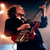 Two side-by-side frames of a pixelated animated icon showing musicians playing electric guitars on stage with stage lighting.