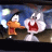 Pixelated static image of two cartoon characters, one orange with a black beak and white face on the left, another white with red mouth and large eyes on the right, against a blue background with light effects.