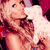 A woman with long blonde hair holds a white stuffed animal against a red background, her expression shifting slightly across frames.