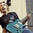 six pixelated showing a person with dark hair playing a blue electric guitar, alongside text elements and symbols on colored backgrounds