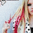 Pixelated image of a person with long blonde hair and red streaks, wearing a black-and-white patterned top against a light background.