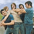 Group of five people in casual clothing standing outdoors with arms around each other, some faces partially obscured.