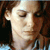 Two side-by-side pixelated images of a person with brown hair wearing a light blue and white striped shirt against a dark background.
