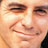 Pixelated close-up of a person's face with visible eyes, nose, and mouth on a light background.