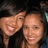 Two people with light brown hair smiling closely together against a dark background, one person's arm visible on the left side.