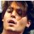 Pixelated close-up of a person's face with dark hair, mouth open in a shout or yell, against a dark background.
