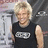 Pixelated image of a person with short blonde hair wearing a dark sleeveless shirt featuring a light-colored rectangular graphic on the chest.