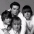 Black-and-white pixelated image of five people in a group pose with text listing names on the right side.