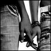 Black-and-white close-up of two hands clasped together, one wearing a striped wristband and the other with visible fingers gripping tightly.