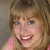 A pixelated image of a smiling person with light brown hair and blue eyes, wearing a pink top, with partial text overlays.