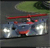 Pixelated static image of a red and blue vehicle with white headlights on a dark road under a greenish sky.
