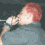 Four of a person with red hair singing into a microphone, wearing a dark gray shirt against a black background