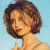 Static pixelated image of a woman with short brown hair against light blue background, wearing strapless top and necklace, making peace sign gesture.