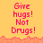 Yellow background with red pixelated text reading 'Give hugs! Not Drugs!' in three , bordered by orange pixelated terrain at the top and bottom