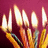 A pixelated image of multiple candle flames against a deep magenta background, with warm yellow and orange hues dominating the flame areas.