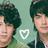 Two individuals with dark hair appear side-by-side against a light green background with a white heart outline in the center.